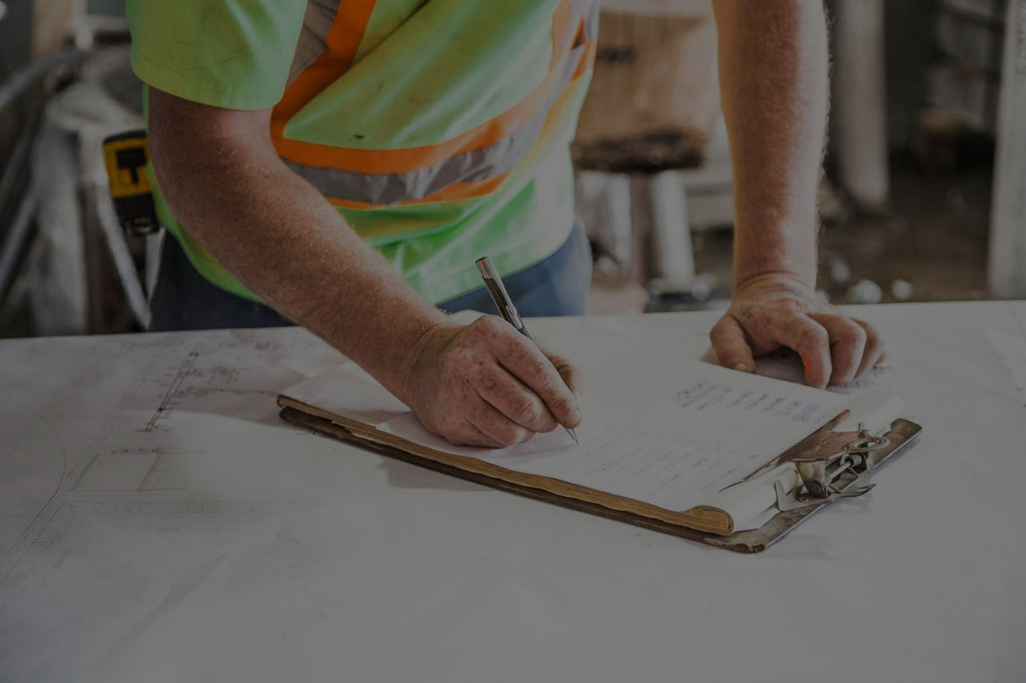 Supervisor realizando una inspección de EPI en el lugar de trabajo, revisando una lista de control para garantizar la seguridad de los empleados.