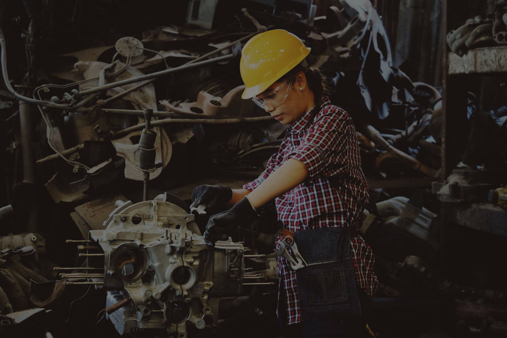 Mujer en taller industrial con casco de seguridad y herramientas, demostrando protección en el entorno de trabajo.