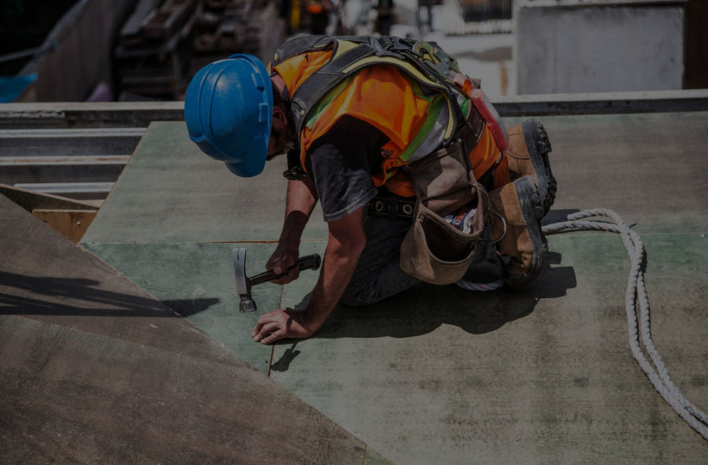 Trabajador de la construcción utilizando un casco de seguridad azul y equipo de protección individual (EPI), trabajando en una obra, resaltando las prácticas de seguridad laboral.