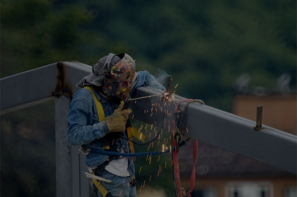 Trabajador soldando en altura con equipo de protección individual (EPI)